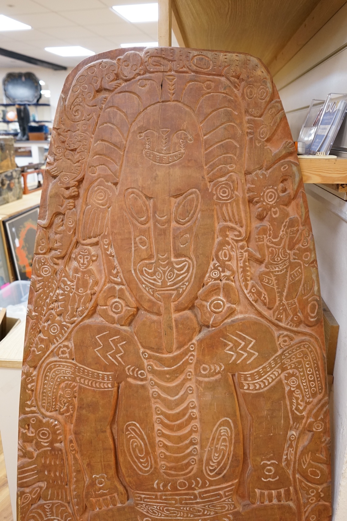 A Papua New Guinea Sepik River large wooden storyboard, relief carved and incised with a central figure surrounded by various animals and spirits, with traces of white pigment, 152cm high